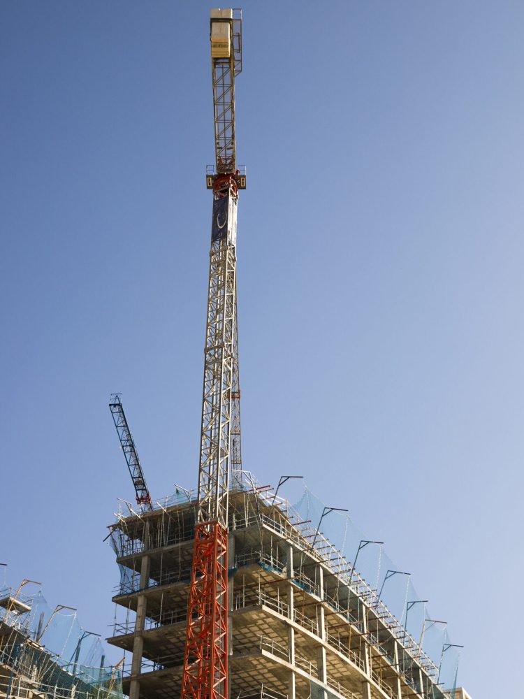 low-angle-view-construction-crane-near-site-against-blue-sky